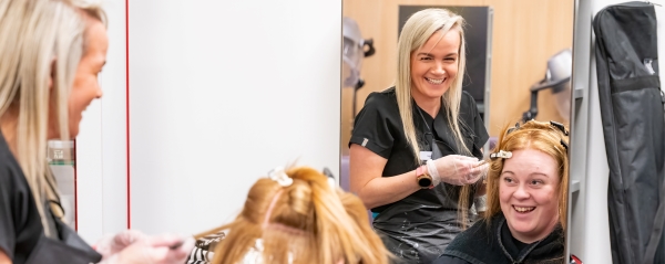 student cutting woman's hair