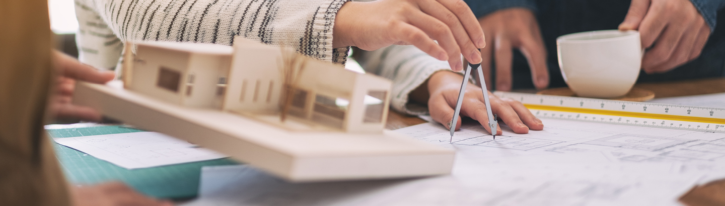Group of architects working and discussing about an architecture model together, with drawing paper on table in office