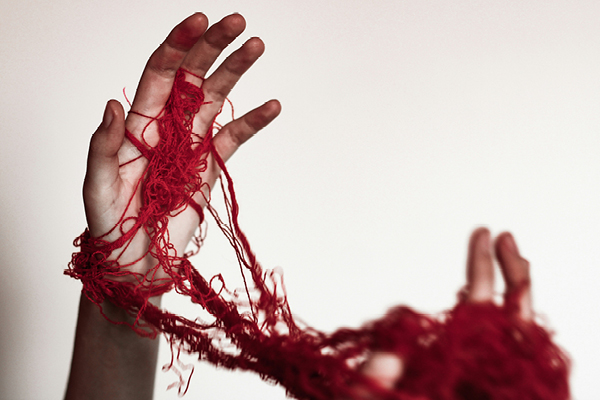 Two hands entangled in red rope