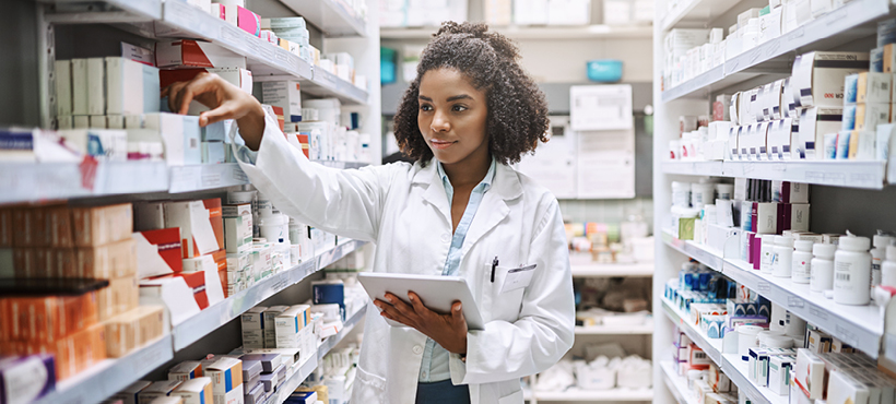 Young pharmacist selecting medicine from shelf