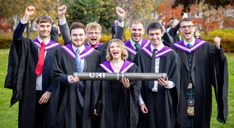 UHI Inverness Graduates holding a large scroll and celebrating