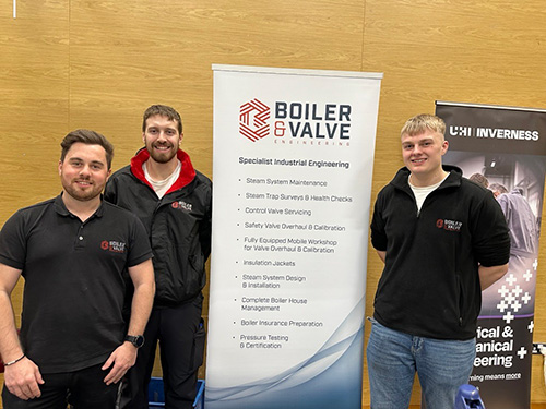 Three men standing by a pop-up banner advertising their company