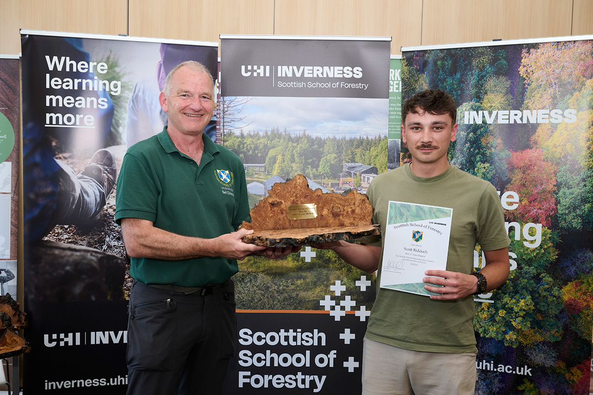 Two men holding up awards