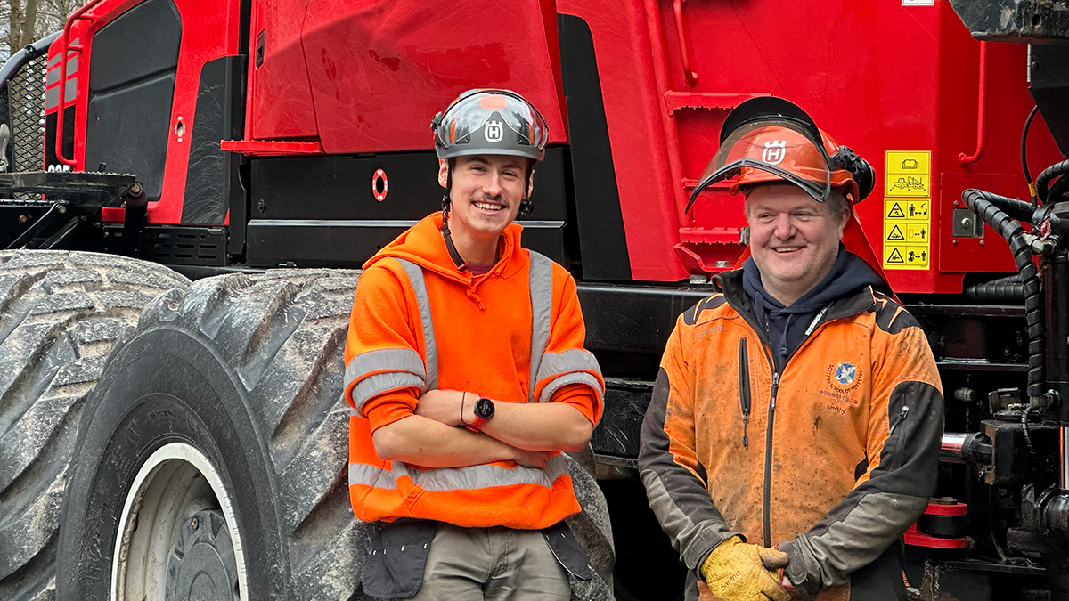 Close up of a student and lecturer in PPE standing by an eight wheeler machine Close up of a student and lecturer in PPE standing by an eight wheeler machine