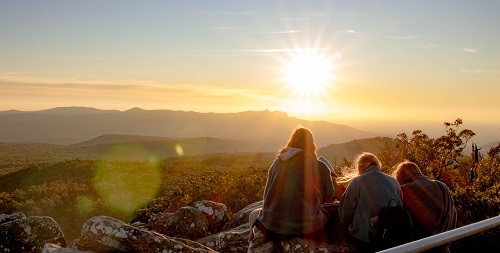 Three people looking out over a sunset landscape