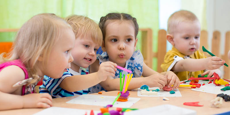 Group of nursery children sat at a table doing arts and crafts