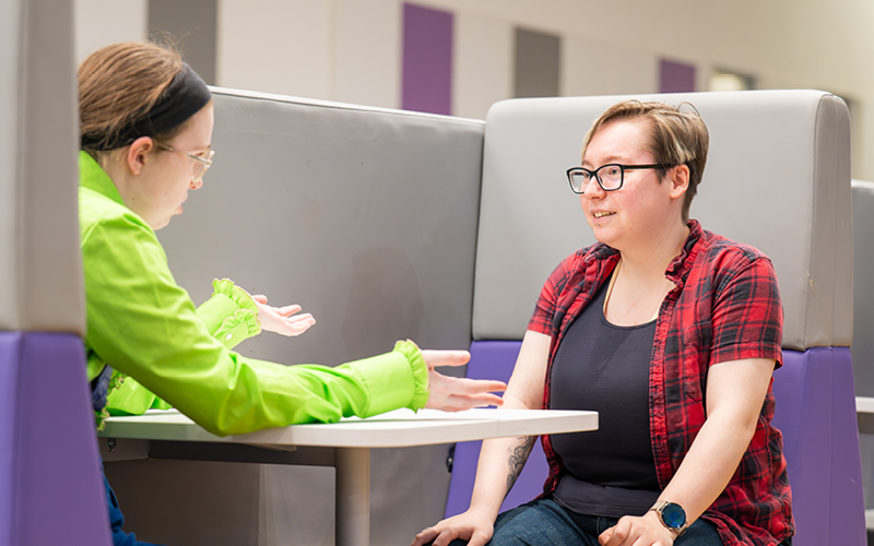 Two UHI Inverness students sitting in the social area having a conversation Two UHI Inverness students sitting in the social area having a conversation