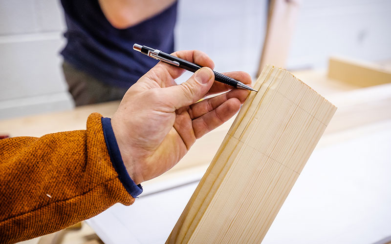 a hand marking wood for cutting