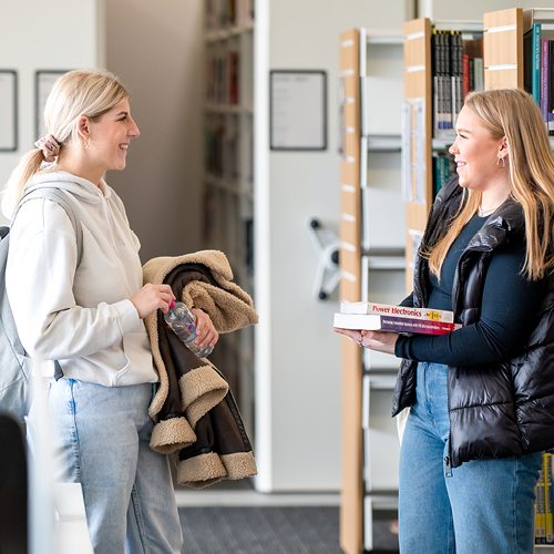 Two people talking in a library