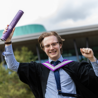 Connor Wright in academic gown holding scroll