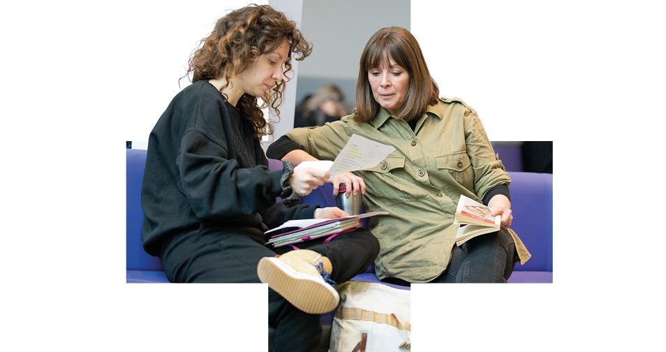 Two people sitting together looking at printed materials