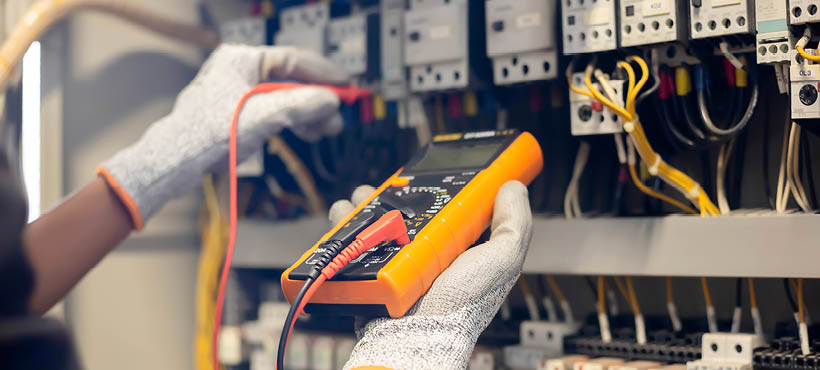electrician using a digital multimeter to test or troubleshoot an electrical panel. electrician using a digital multimeter to test or troubleshoot an electrical panel.