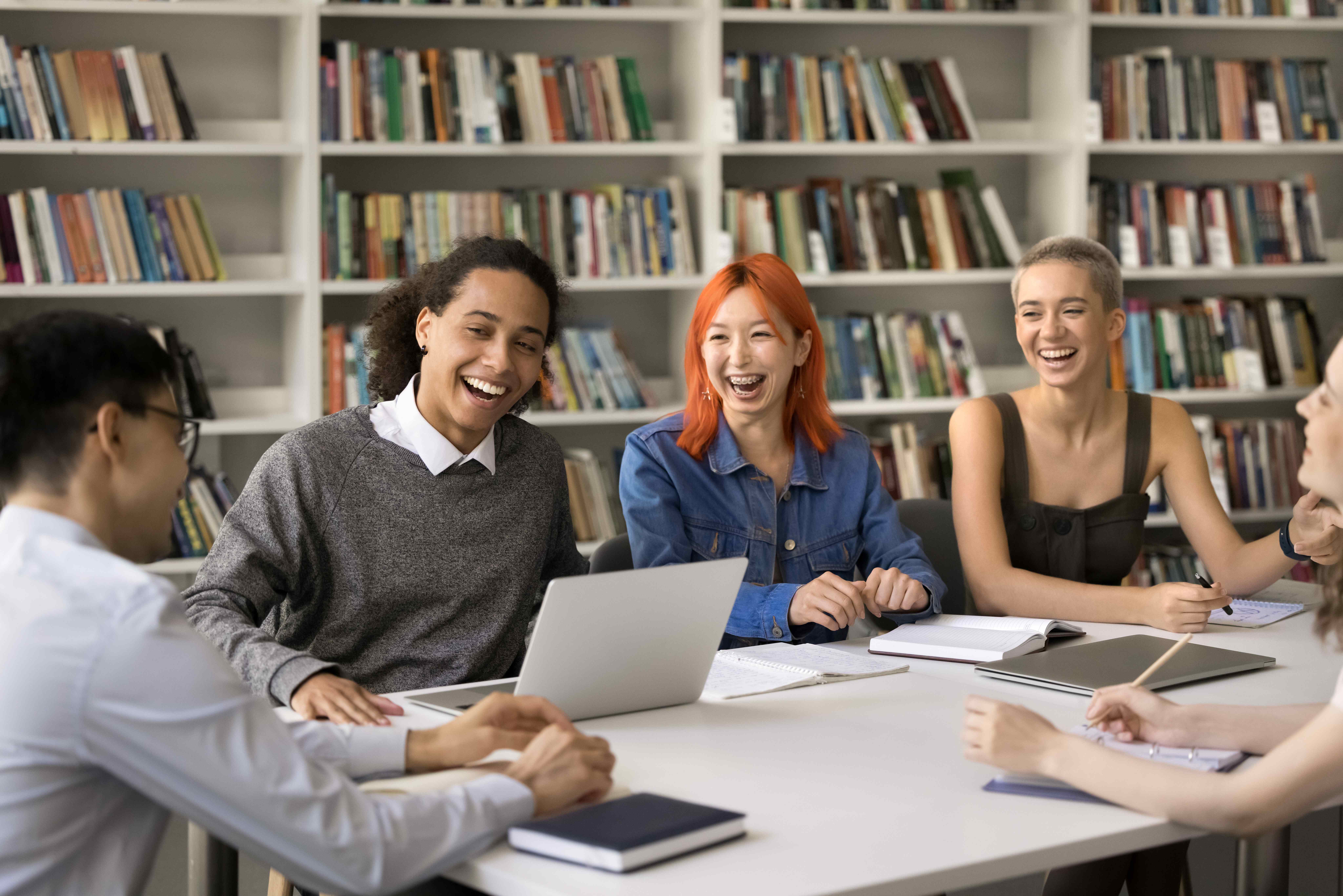 students at a table laughing in the library students at a table laughing in the library