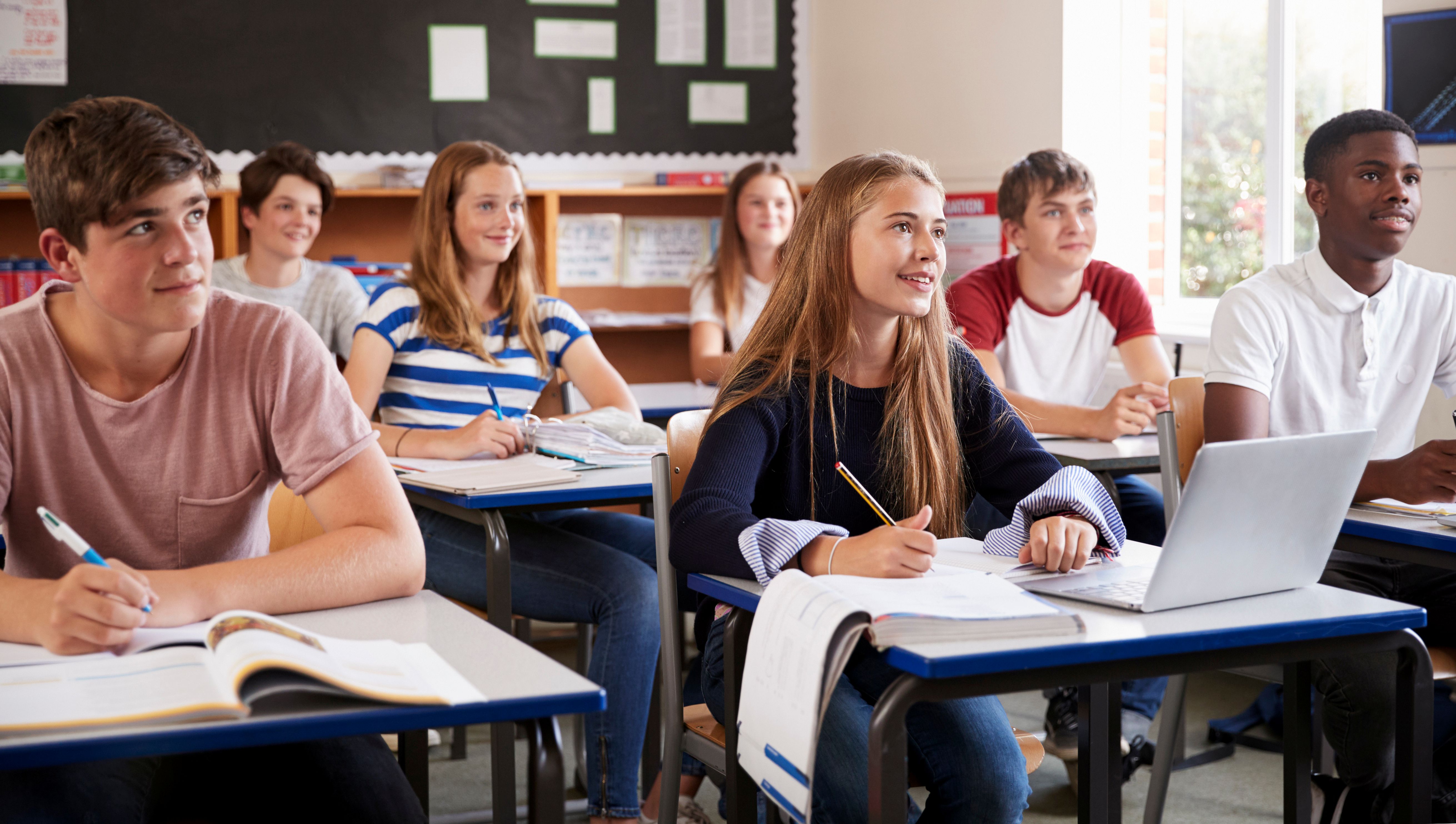 students at single desks in a classroom students at single desks in a classroom