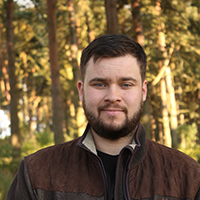 Student standing in front of trees